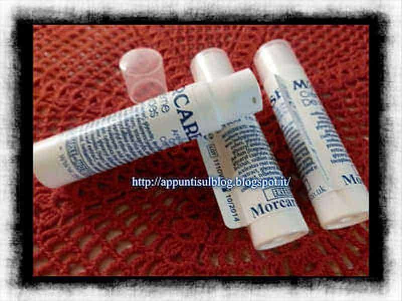 Morcare, pelle perfetta con rimedi naturali 3 Cura delle labbra secche con balsamo idratante, applicato su una superficie rossa a maglia, evidenziando prodotti per l'igiene orale e la cura personale.