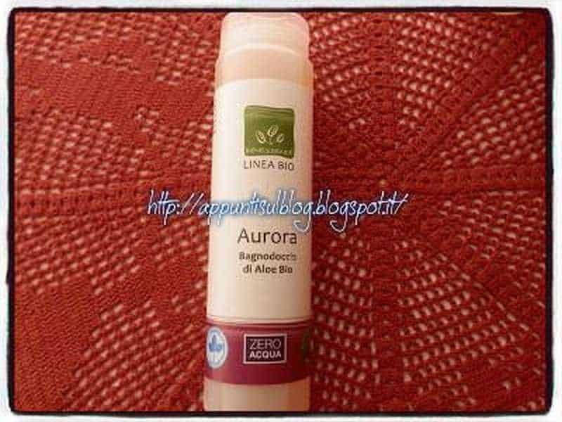 Benessence linea Bio con Aloe Vera, amica della pelle 4 Pianta Aurora di Aloe Bio in flacone, pronto all'uso, senza acqua, ideale per prodotti naturali e biotecnologie verdi, su sfondo tessile rosso.