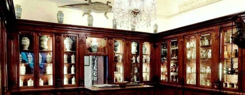 Vetrina in legno con antiquati vasi di ceramica e decorazioni d'epoca, ambiente elegante e raffinato.