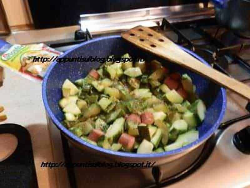 Ragù di zucchine e prosciutto preparato in padella, ideale per un pasto veloce e salutare, visualizzato su una cucina moderna con utensili da cucina in legno a fianco.