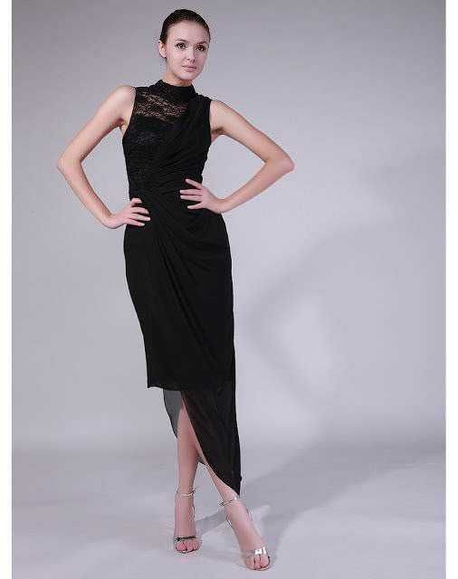 Elegante donna in abito nero lungo con dettaglio in pizzo sulla parte superiore, posa con sicurezza su sfondo neutro. Perfetta per eventi formali, moda e stile.