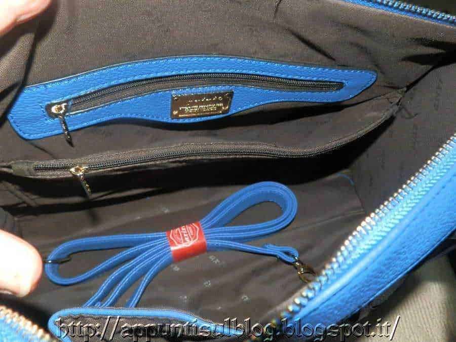 Fondo interno della borsa con tasche e cerniere, dettagli in blu e nero, include corda elastica rossa e blu, ideale per organizzare accessori e dispositivi elettronici, più spazio e praticità per il trasporto.