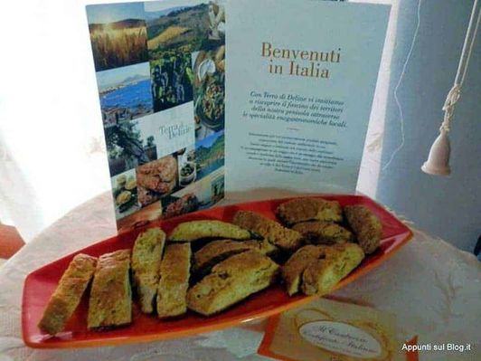 Terra di Delizie, i sapori artigianali italiani di casa nostra 2 Fritti misti italiani su piatto di ceramica rossa, con brochure informativa di benvenuto in Italia sullo sfondo.