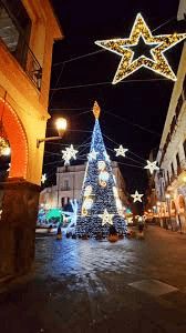 Albero di Natale decorato con luci e stelle luminose in centro città durante le festività natalizie.