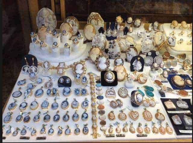 Eleganti uomini e donna sorridenti in negozio di gioielli con collezioni di collane e orecchini in esposizione.