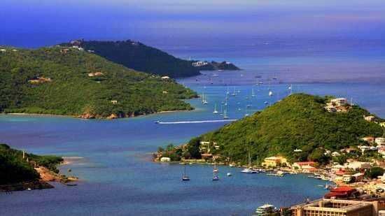 Baia panoramica con acque turchesi, barche ormeggiate e colline verdi, in una scena mozzafiato di un paradiso mediterraneo ricco di natura e tranquillità.