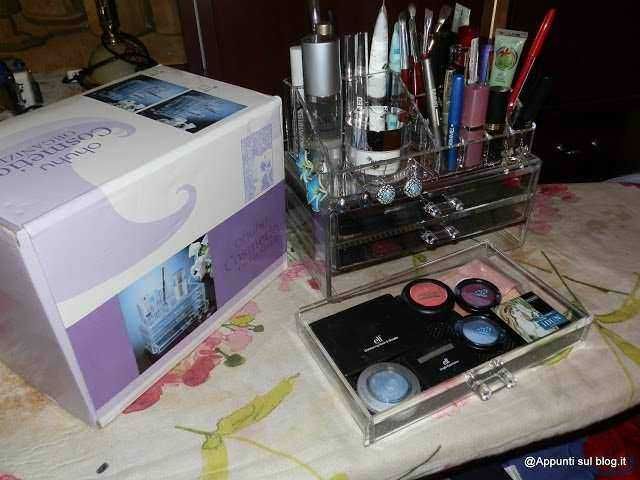 Pennello e prodotti per il trucco, organizzati in contenitori trasparenti su una superficie con decorazioni floreali.