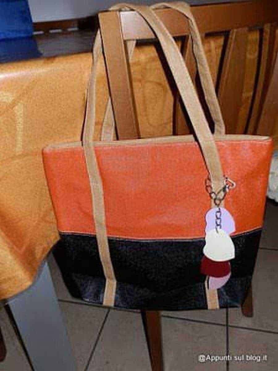Borsa tote in tessuto colorato con dettagli beige e accessori moda, appoggiata su una sedia di legno. Perfetta come accessorio moda casual e versatile. Ideale per outfit estivi e quotidiani.