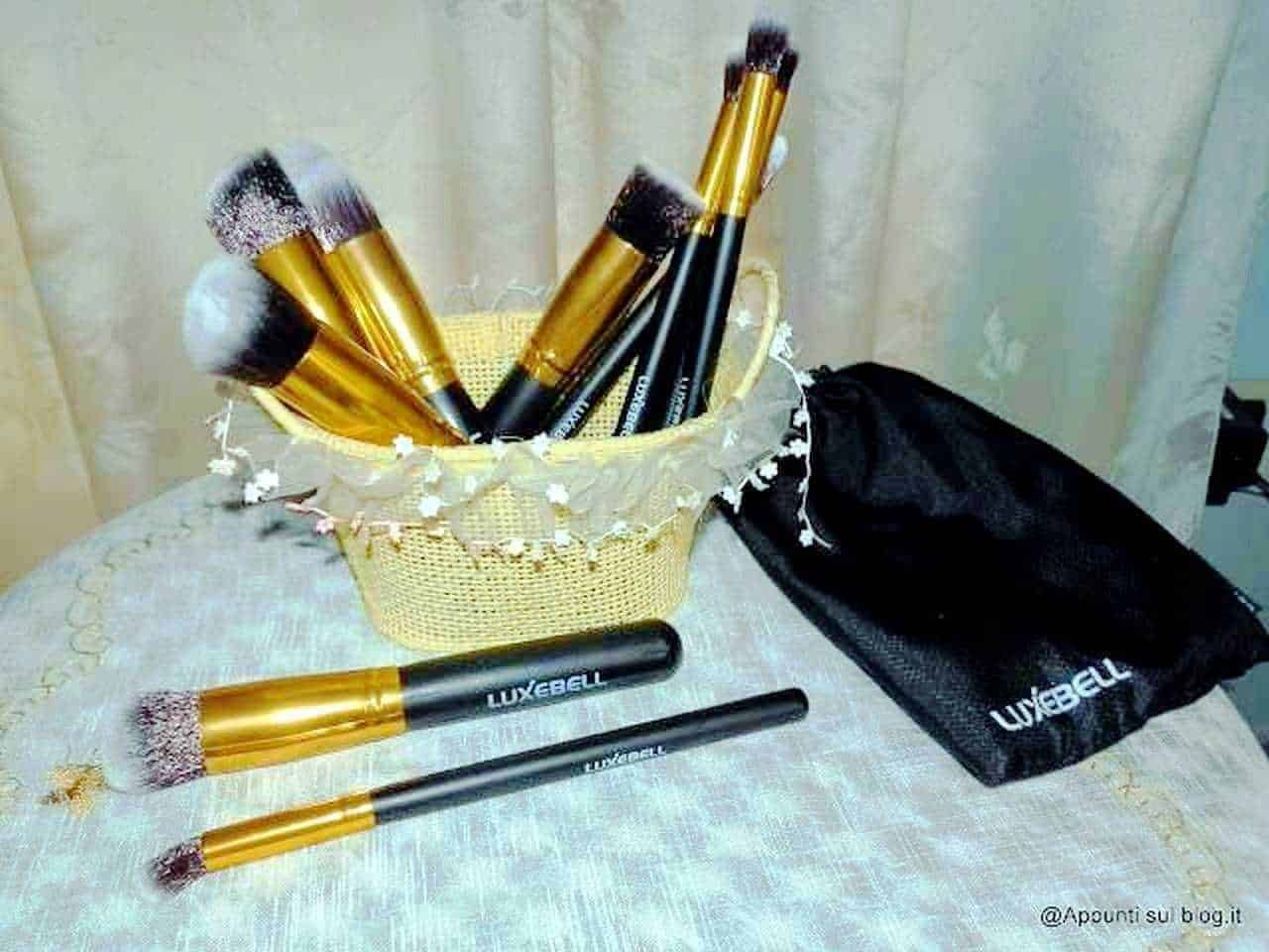 Pennelli da trucco con manici neri e bocchini dorati, disposti in un cestino decorato, con due pennelli extra sopra il tavolo. Set di strumenti di bellezza per trucco professionale o amatoriale.