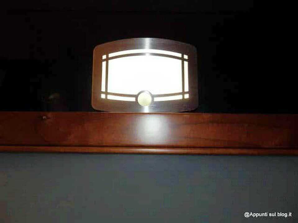 LAMPADA DA TOELETTATURA MODERNA SU MURO INOSERVATO, ILLUMINAZIONE SOFT PER SPAZI INTERNI, DESIGN ELEGANTE IN METALLO E VETRO, IDEALE PER BAGNO O CORRIDOIO.