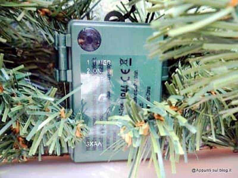 Blue official ID card partially hidden among green plastic bushes for security and identification purposes.