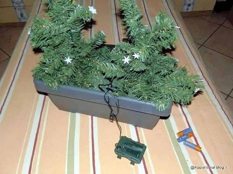 Albero di Natale artificiale in oasi, decorato con luci e fiocchi di neve, pronto per essere allestito durante le festività natalizie.