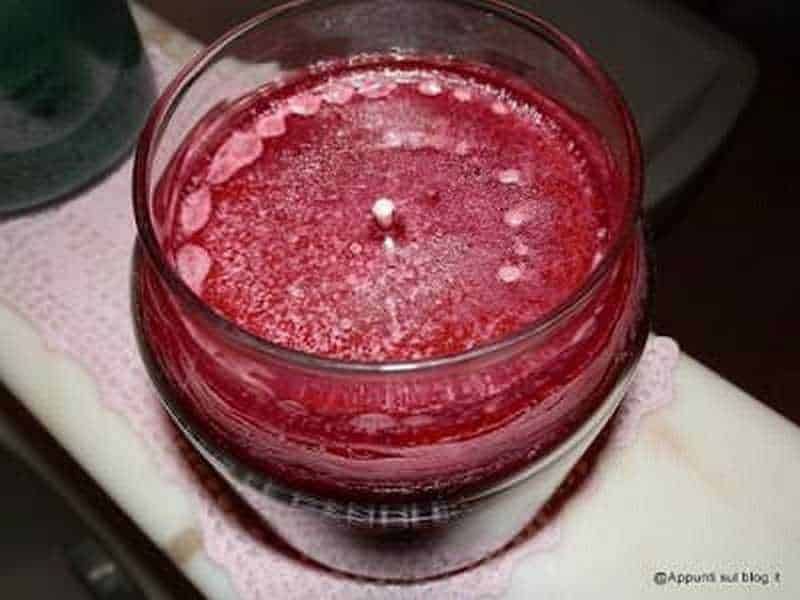 Candele Yankee, relax con profumo, luce e colore 5 Fragranza di candela viola con cera solida in vasetto di vetro, ambientata in un contesto domestico elegante e accogliente.