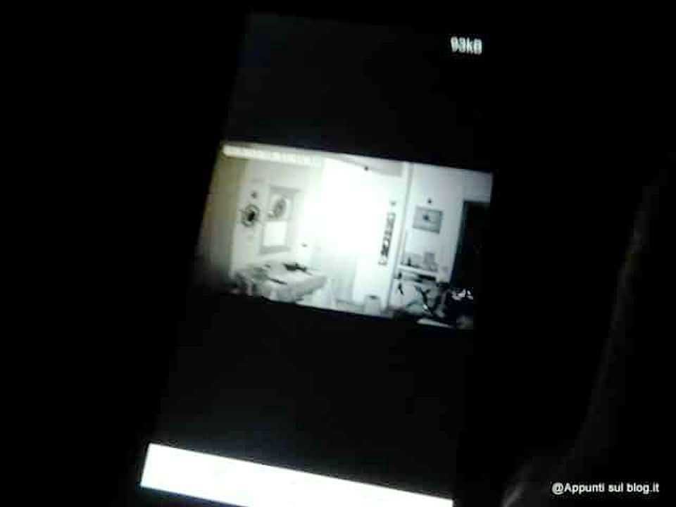 Uno screenshot di una stanza da letto luminosa, visualizzata su uno schermo di un dispositivo digitale, probabilmente un telefono o un tablet, con un'atmosfera contemporanea e minimalista.
