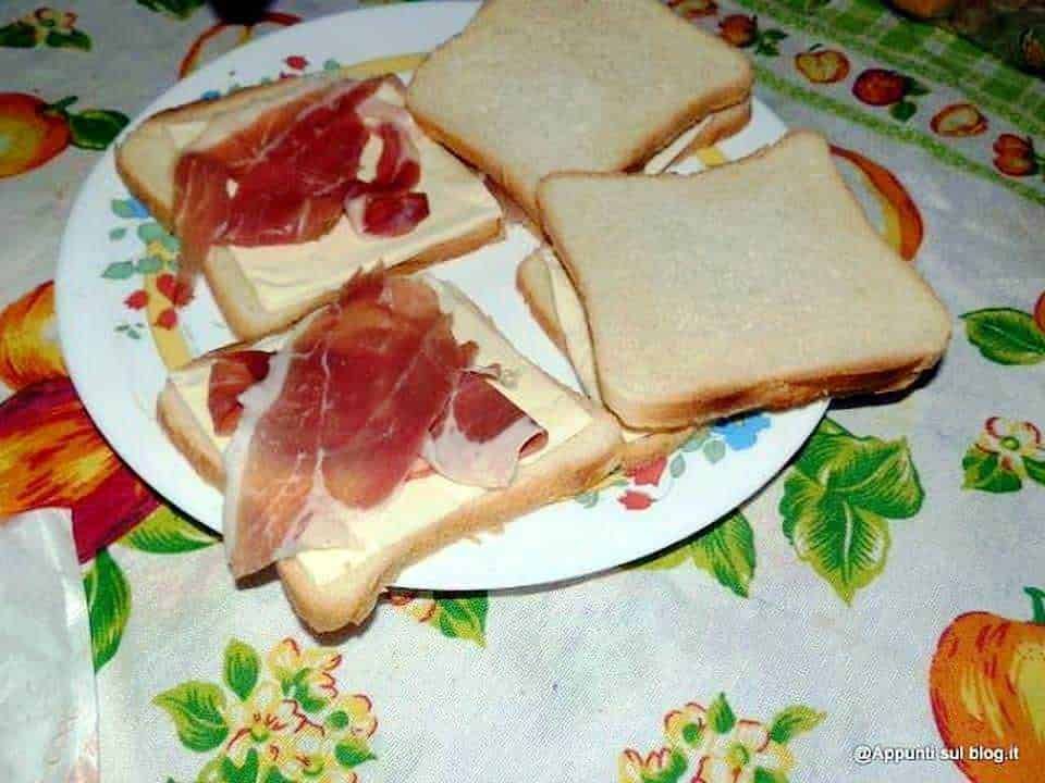 Fette di pane con prosciutto e formaggio, ideale per spuntino o colazione gustosa. Presenta un abbinamento classico di sapori italiani, perfetto per ogni momento della giornata.