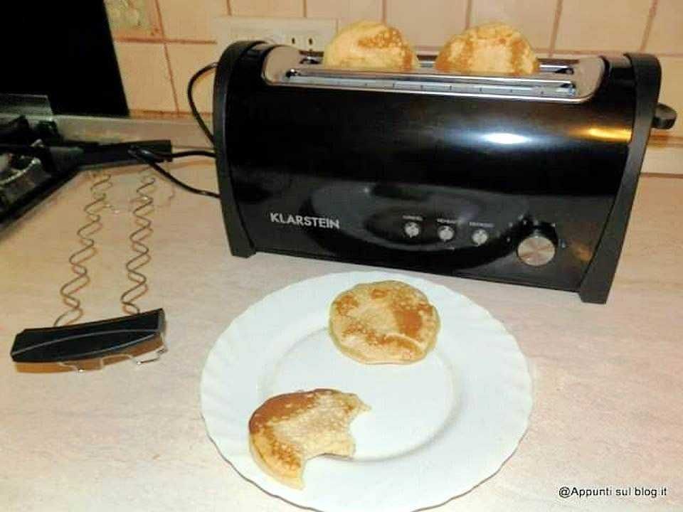Tostapane nero con pane bruciato pronto, con due fette di pane in ammaccature, in ambiente domestico.