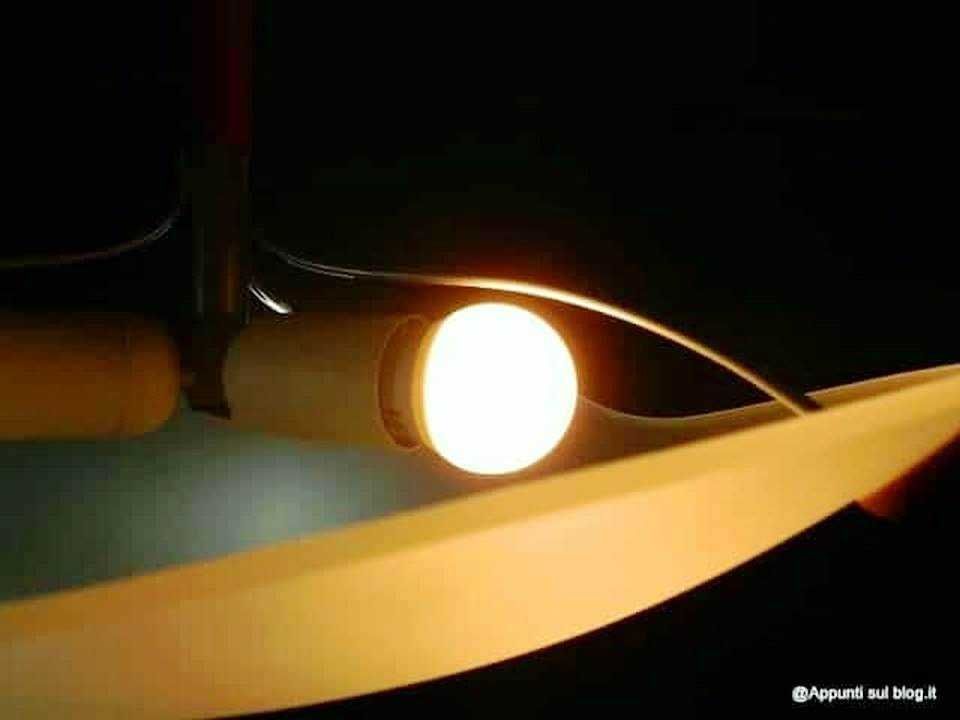 Lampada da tavolo accesa con luce calda su scrivania, ambiente di lavoro o studio, illuminazione morbida ed accogliente per lettura o scrittura, ideale per shop online o blog di lifestyle.