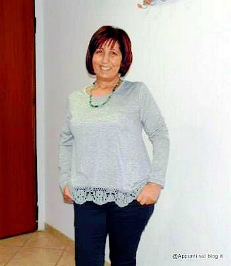 T-shirt a fiori long sleeve crochet: Elegante donna con capelli corti e rosso castano, indossa maglia grigia stile casual e pantaloni scuri, in ambientazione domestica, sorridente e sicura di sé.