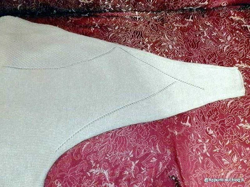 Seta bianca decorativa su tessuto rosso con motivi floreali, dettaglio di tessuto pregiato, eleganza e stile, decorazione di alta qualità, ambientazione di lusso, tappeto raffinato, artigianato italiano, design elegante, materiale di qualità, texture ricercata, abbigliamento sofisticato, arredamento di classe.