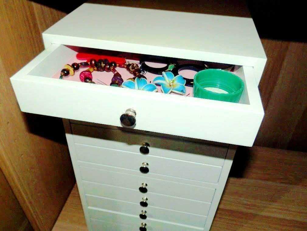 Braccialetti di plastica colorati e collane di bigiotteria su un mobile bianco con cassetti, oggetti di moda e accessori moda, spazio di archiviazione per accessori di moda.