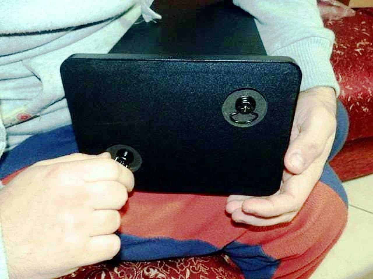 Schermo di un tablet nero con supporto rotante, mani di una persona che lo tengono, uso di tecnologia digitale, dispositivo mobile, connessione e intrattenimento digitale.