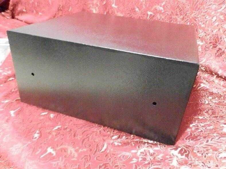 Tanica di metallo nera per conservare liquidi o materiali di laboratorio, robusta e resistente, su sfondo rosa con motivo floreale.