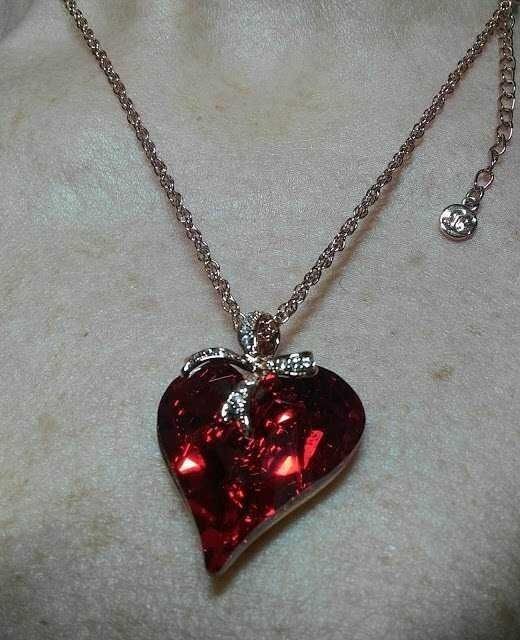 Collana con pendente a forma di cuore rosso brillante, ornata da dettagli in argento, ideale come regalo romantico o accessorio di moda elegante.
