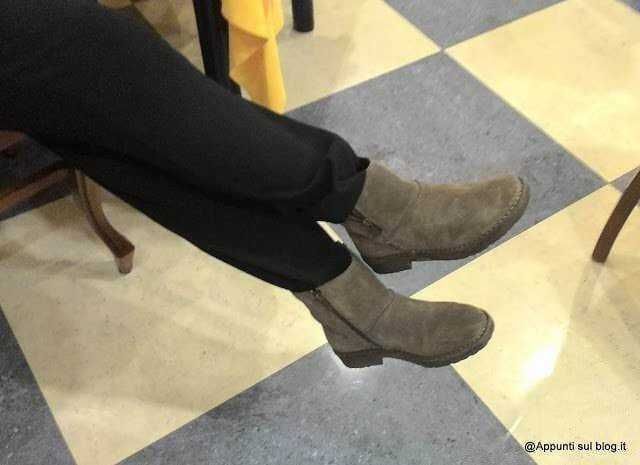 Scarpe da uomo eleganti in pelle, stivali marroni, seduti su sedia su pavimento a scacchi in un locale pubblico.