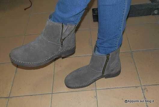 Stivaletti in pelle scamosciata grigia con zip laterale indossati con jeans blu, in ambientazione interna su piastrelle beige. Perfetti per stile casual e comfort quotidiano.