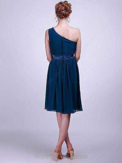 Elegante donna con abito blu a una spalla, sfondo neutro, stile sofisticato e femminile, perfetto per eventi formali o serate speciali.