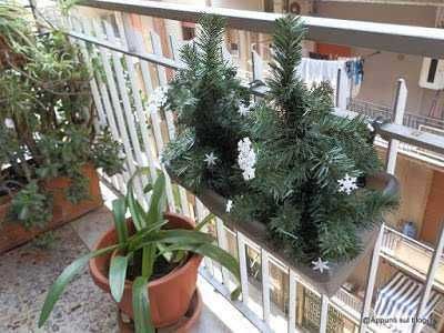 Addobbo natalizio con pino artificiale decorato con fiocchi di neve in una fioriera sul balcone. Perfetto per decorare la casa durante le festività natalizie. Idee di decorazioni di Natale fai-da-te.