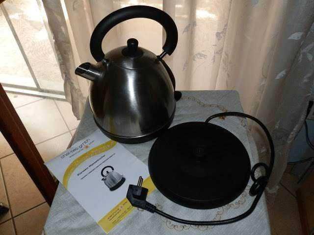 Pentola a piastra elettrica e teiera in acciaio inox, accessori da cucina moderni, elettrodomestici per cucinare, configurazione su tavolo vicino a finestra.