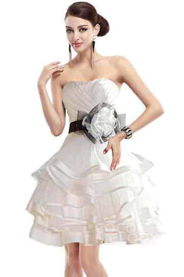 Elegante donna in abito bianco con cintura nera e accessori moda, posa su sfondo bianco, stile sofisticato e chic.