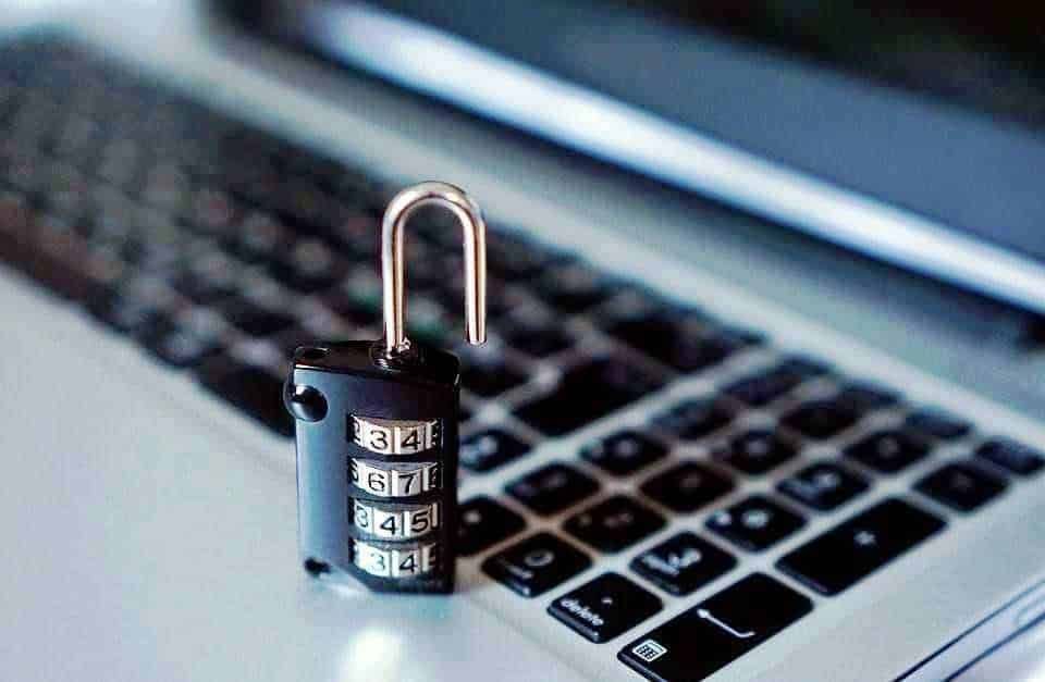 Consigli per viaggiare da sole in sicurezza: Sicurezza informatica, lucchetto con combinazione su tastiera di laptop per protezione dati digitali, cyber sicurezza, privacy online.