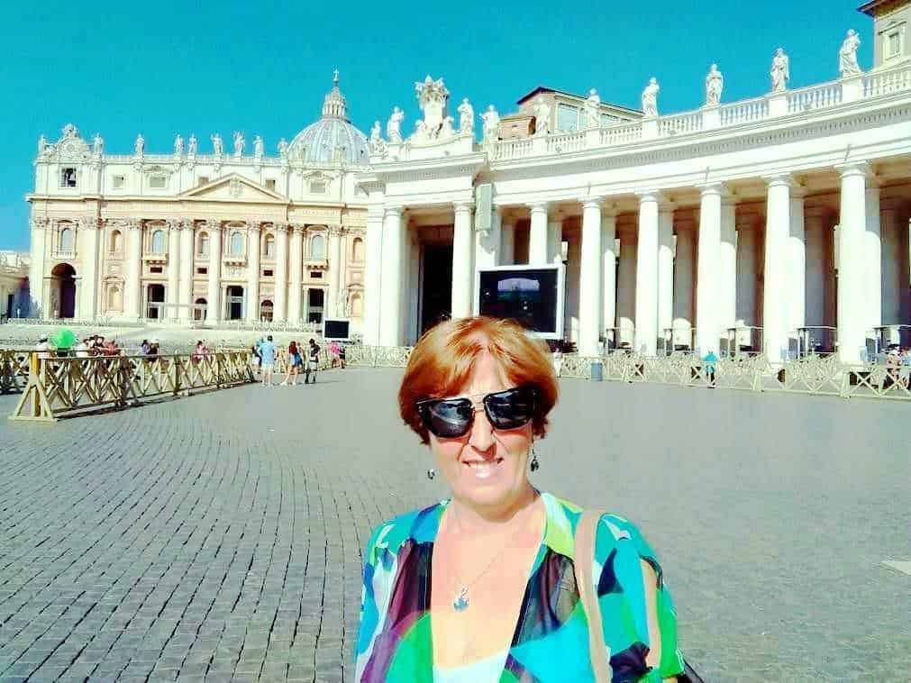 Majestosa Basilica di San Pietro a Roma con visitatrice sorridente in primo piano, abbigliamento colorato, giornate soleggiate, turisti, architettura storica, pellegrini.