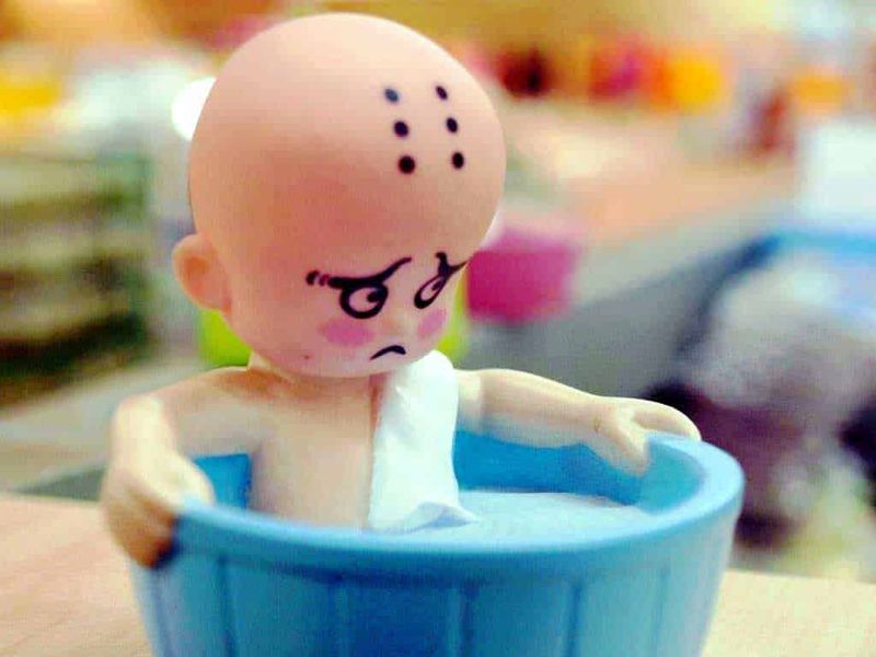 Bagnetto Neonato in Vasca o Doccia: Guida Pratica e Consigli Utili 3 Soppalco con vaschetta di acqua, figurina di cartone con espressione triste, personaggio triste e abbandonato, decorazioni colorate in background, immagine di giocattoli in ambienti per bambini.