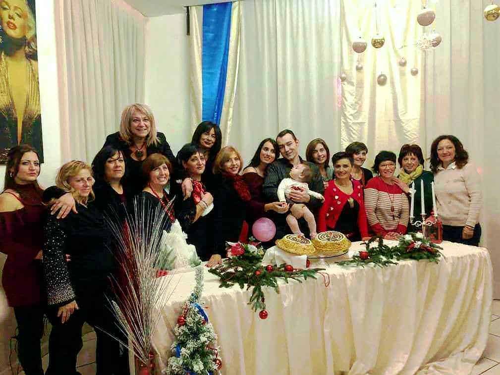 Gruppo di persone festeggiando con dolci natalizi e decorazioni festive, in un evento allegro e conviviale, perfetto per momenti di celebrazione e socializzazione durante le festività.