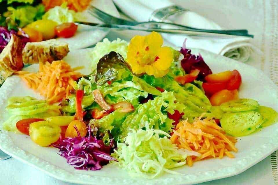 Fondo di insalata mista con verdure fresche e colorate, dettaglio di un piatto di insalata variopinta, antica fotografia di insalata di verdure miste con condimento, rilevanza alta per blog di ricette e alimentazione sana.