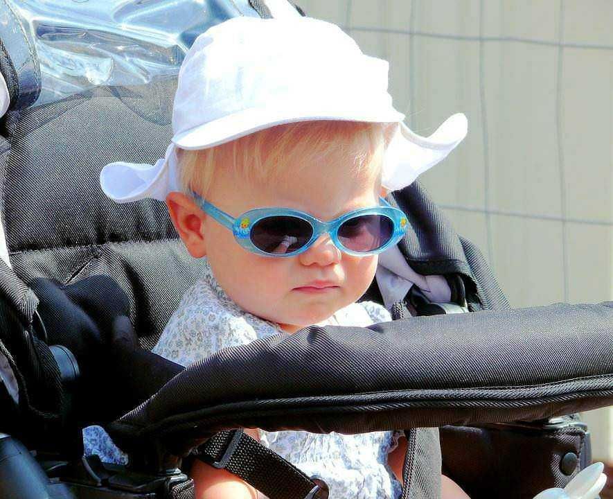 Disneyland bambino occhiali da sole estate, bambino in passeggino, look estivo con cappello bianco, atmosfera felice, divertimento in famiglia, gadget per bambini, moda estiva per bambini, accessori per bambini, foto di viaggio, eventi per famiglie.