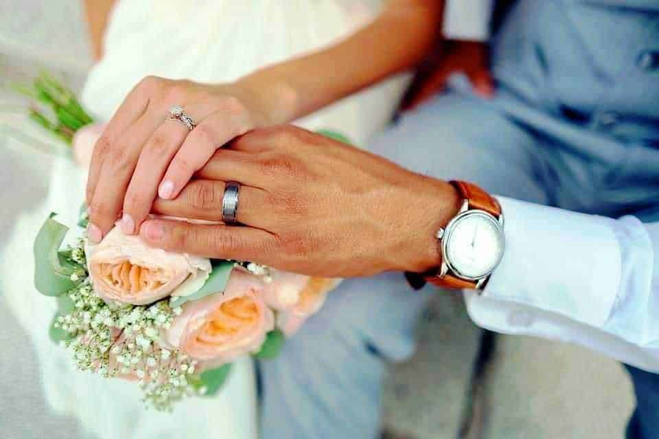 Anelli di coppia e bouquet di fiori romantici, simbolo di amore e unione durante il matrimonio.