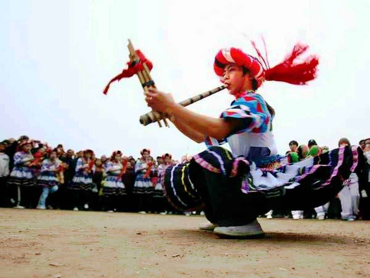 Bambina che suona il flauto occidentale durante una festa tradizionale con un gruppo di persone in abiti folkloristici, ambiente aperto, cielo nuvoloso, cultura e tradizioni popolari italiane.