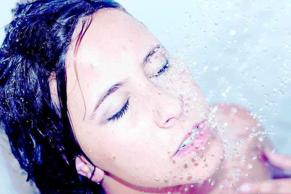 Lucia in acqua con acqua che scorre sul viso, bellezza naturale, relax, cura della pelle, benessere, immagine di relax e skincare, scena di benessere e cura personale, rinfrescata e rigenerata, atmosfera di relax e cura del corpo, immagine di benessere e cura della pelle.