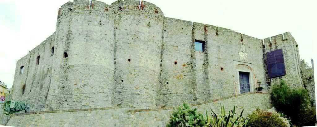 Castello medievale in pietra con mura robuste, torri e finestre, situato su una collina con vegetazione circostante, esempio di architettura storica e patrimonio culturale italiano.