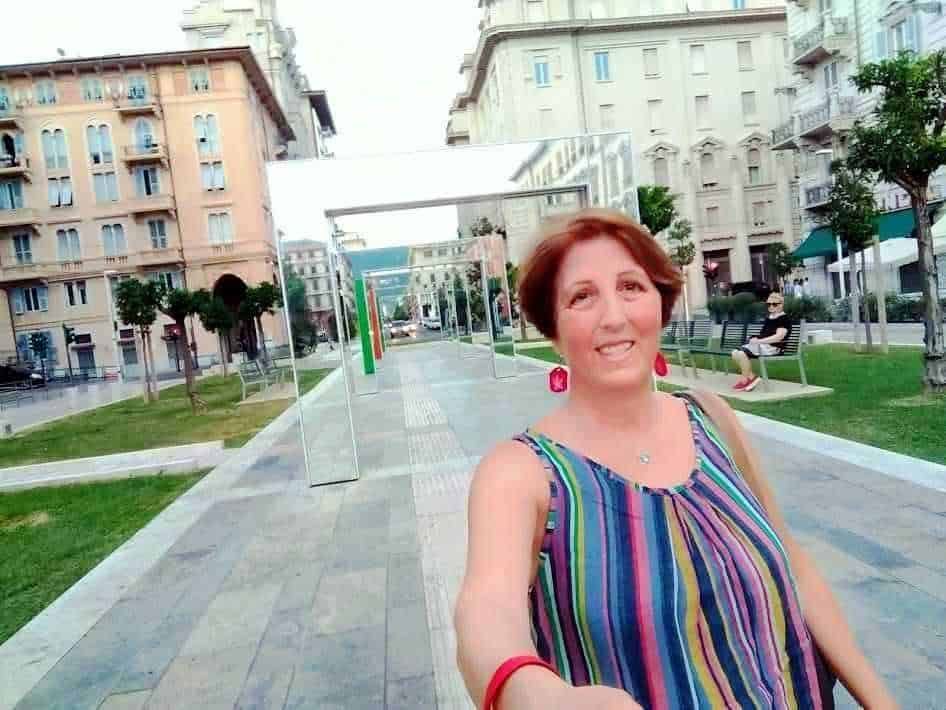 Appunti sul blog donna in strada con abbigliamento colorato e sorriso, ambientazione urbana, parco e architettura storica, ottima per contenuti di lifestyle e viaggi, immagini di giornali e blog di lifestyle.