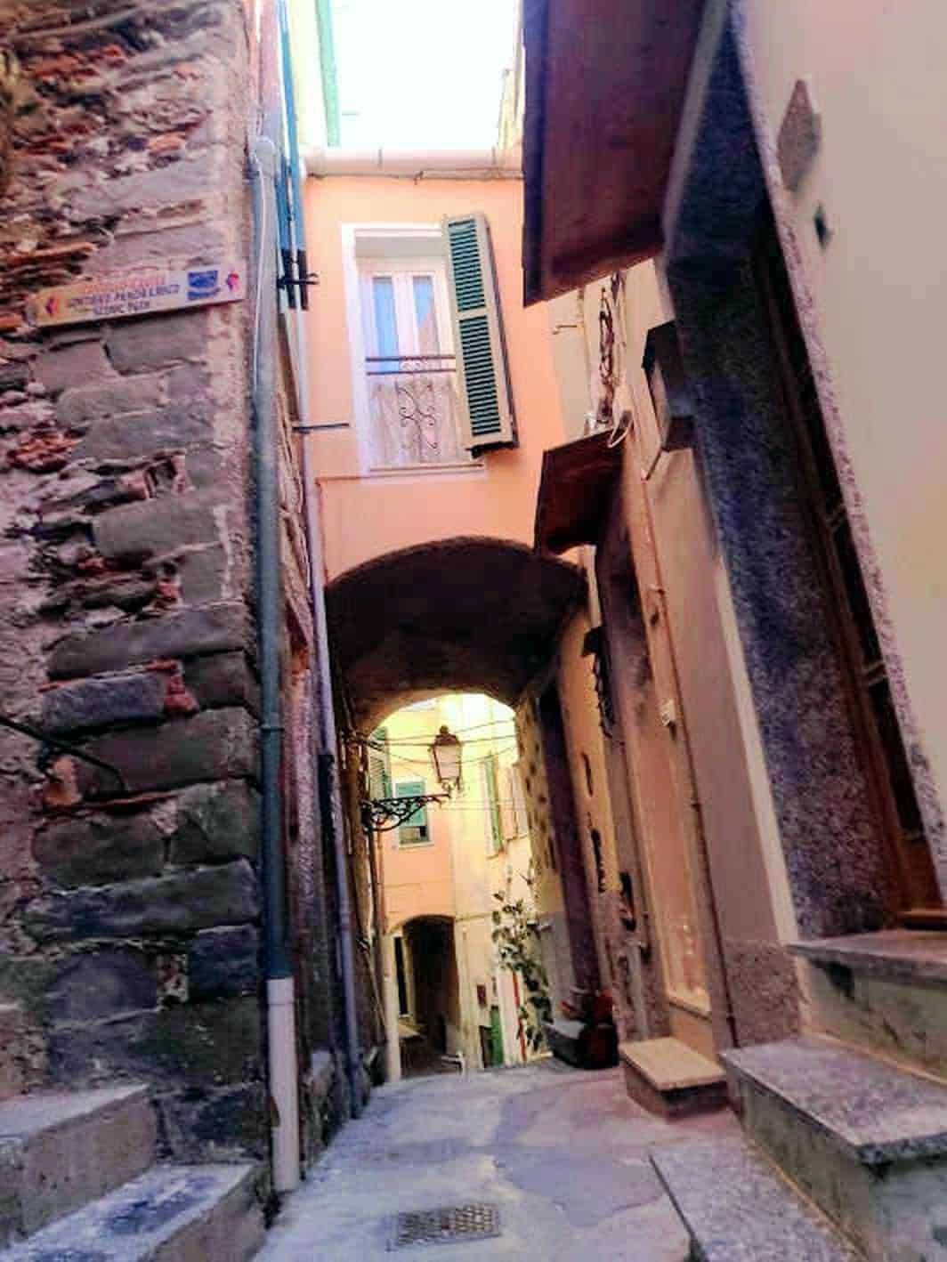 Vecchio vicolo in Italia con case colorate, archi e lampioni, rappresentazione di charme e autenticità locale.