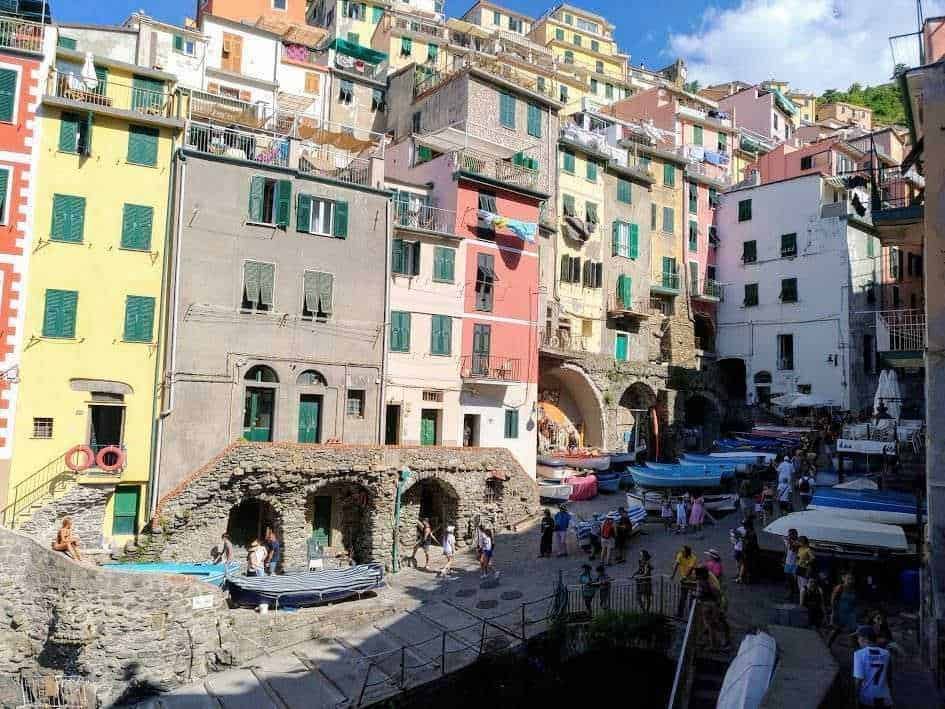 Colorati edifici sul lungomare di Monterosso al Mare, Cinque Terre, Liguria, Italia, con barche ormeggiate e turisti che passeggiano lungo la costa, scenario pittoresco e vivace.