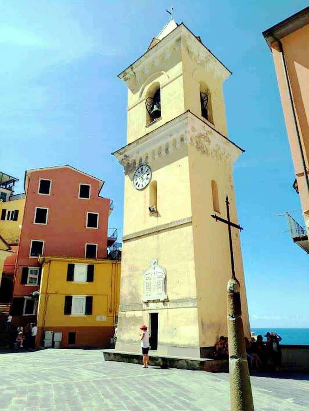 Antico orologio a Torre, stile medievale, nei caratteristici quartieri di pescatori di Vernazza, Cinque Terre, Italia, con case colorate e vista sul mare.