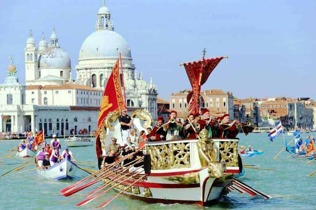 Voga alla veneta su un tradizionale barco in canal grande di Venezia, con il fondo delle iconiche cupole della Basilica di Santa Maria della Salute.