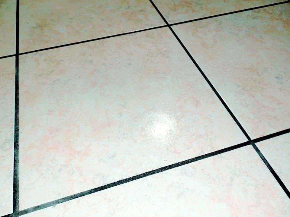 Lastre di piastrelle beige con linee nere di fuga, pavimento di ceramica semplice e funzionale, ideale per ambienti interni come cucine e bagni, facile da pulire e resistente all'usura.