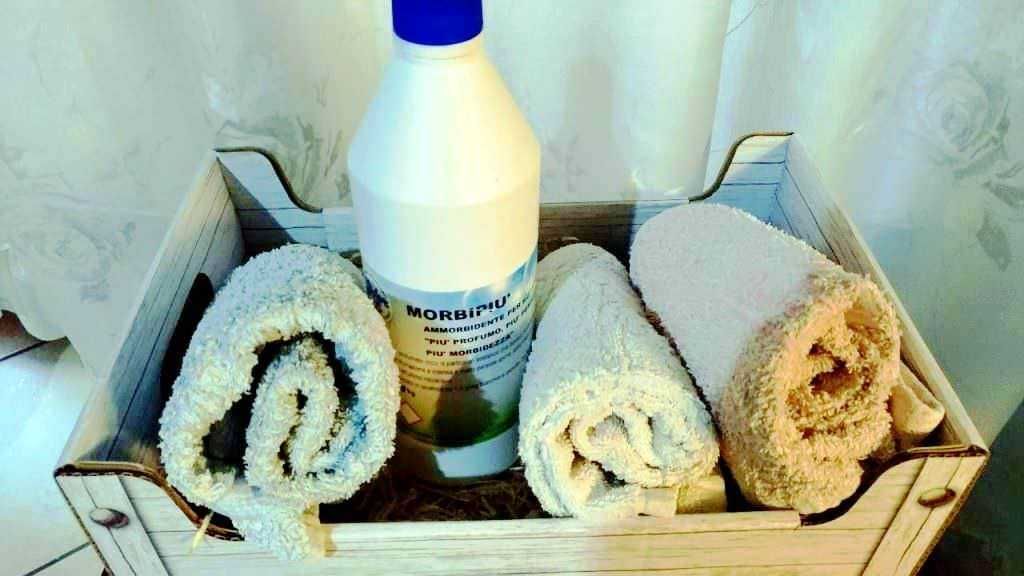 Odore di pulito e benessere con morbidi asciugamani e detergente per il bucato in un elegante cesto in legno. Perfetto per ambienti domestici e cura personale.